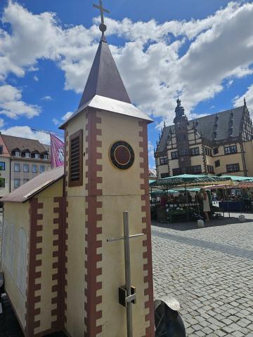 Die Wagenkirche bei leicht bewölkten blauem Himmel vor dem Schweinfurter Rathaus