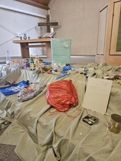 verschiedenste Plastikmüllteile liegen auf den Stufen zum Altar. Im Hintergrund das einfache Holzkreuz der Kirche